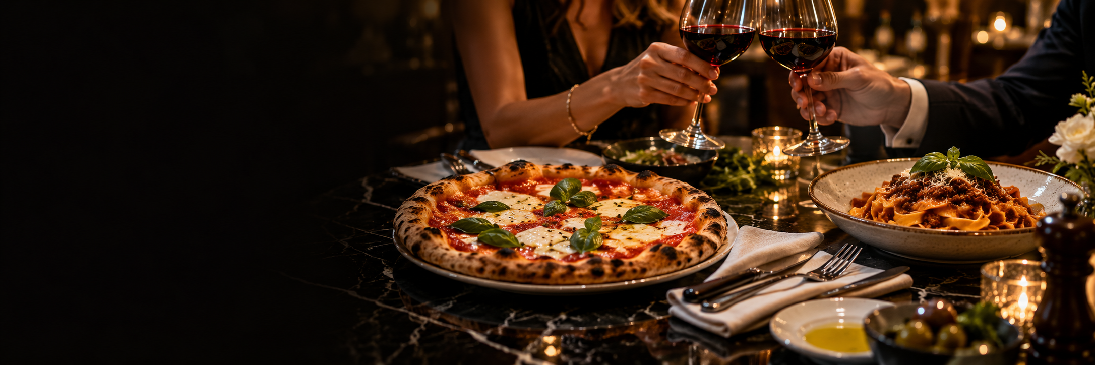 Pizza y pasta servidas en una mesa elegante mientras dos personas brindan